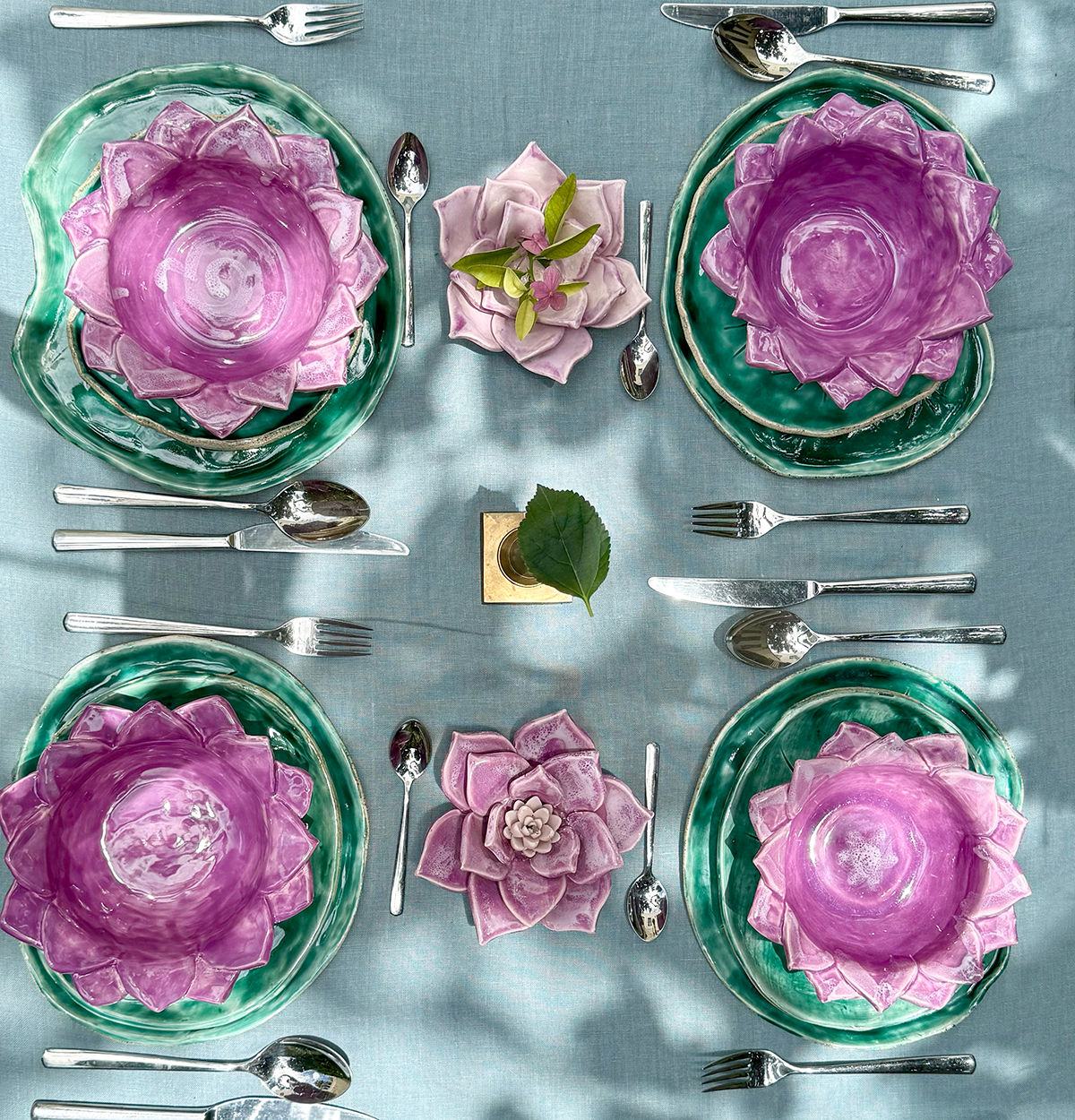Vajilla de cerámica con platos y bowl en forma de la flor y las hojas, simulando un jardín de nenúfares flotantes en la mesa.