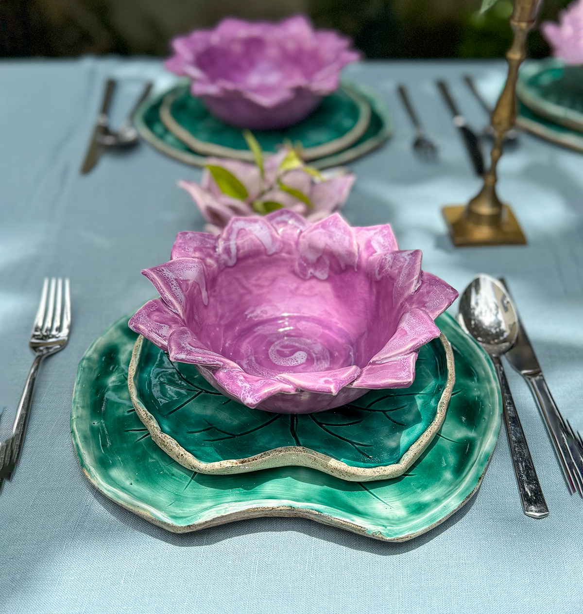 Vajilla de cerámica con platos y bowl en forma de la flor y las hojas, simulando un jardín de nenúfares flotantes en la mesa.