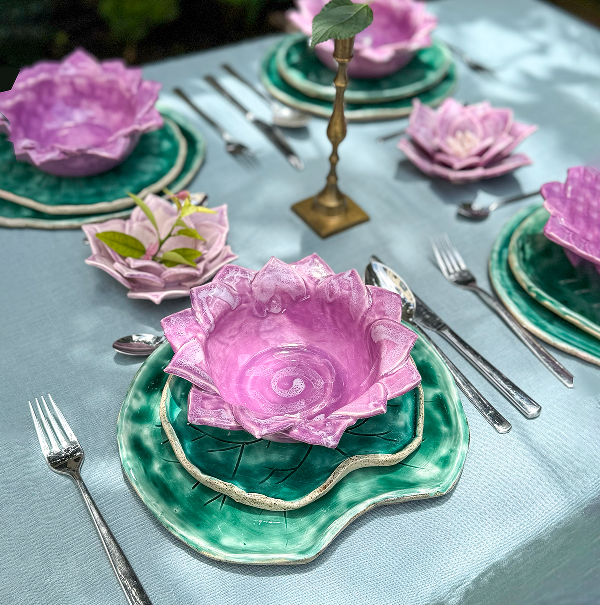 Vajilla de cerámica con platos y bowl en forma de la flor y las hojas, simulando un jardín de nenúfares flotantes en la mesa.
