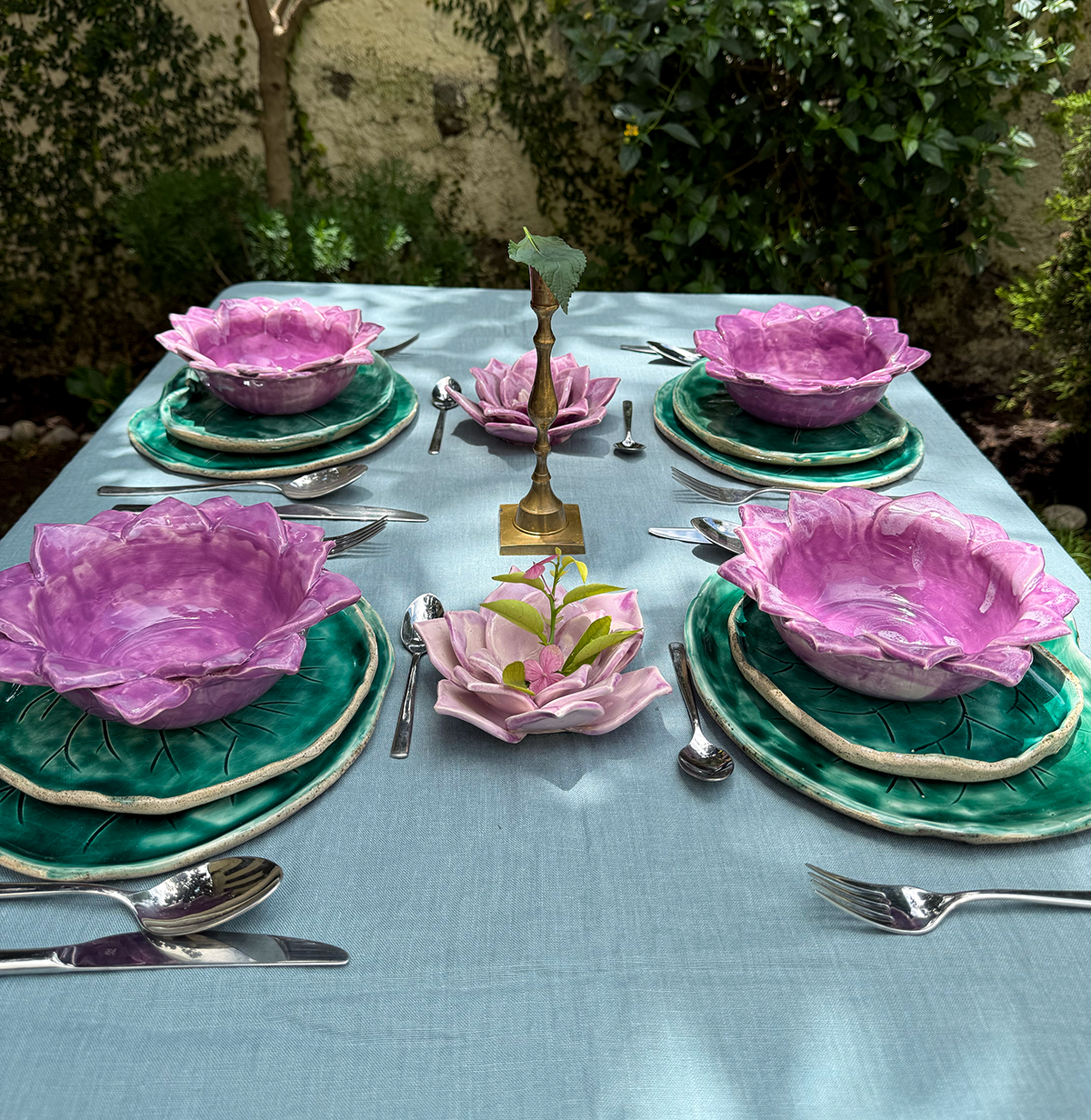 Vajilla de cerámica con platos y bowl en forma de la flor y las hojas, simulando un jardín de nenúfares flotantes en la mesa.