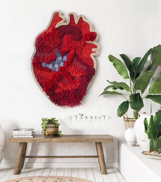 Arte textil en forma de corazón, confeccionado en tonos rojos vibrantes, destacando una variedad de texturas y patrones intrincados